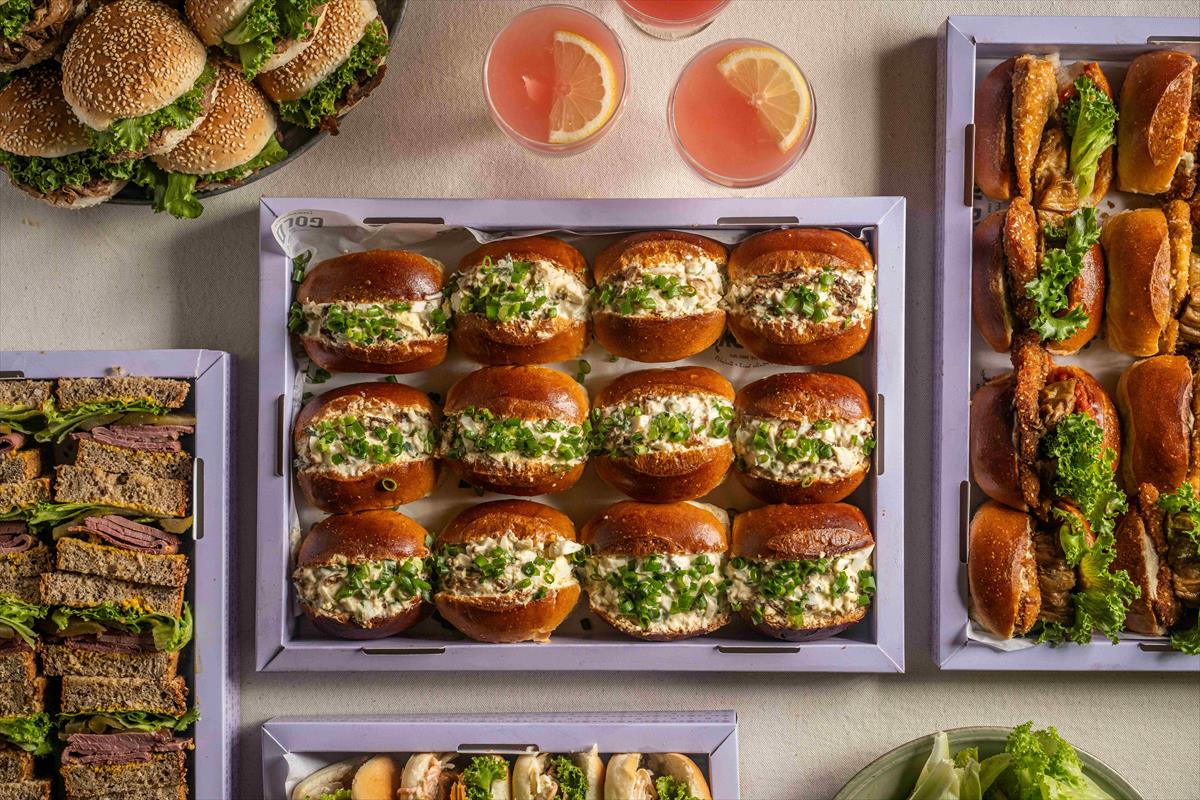 A tray of egg salad and fresh vegetables sandwiches on grains flute