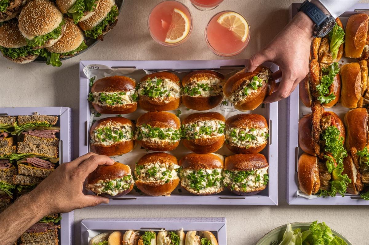 A tray of egg salad and fresh vegetables sandwiches on grains flute